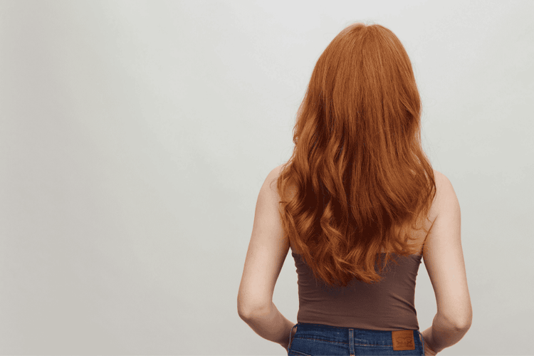 a person with long red hair from the back