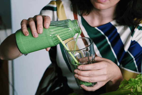 woman making greens powder smoothie